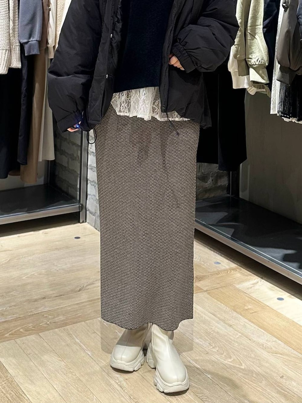 ホワイト系のブーツ、ブラック系のスカート、ブラック系のその他アウターを着用したレディースの冬コーディネートの4枚目の写真