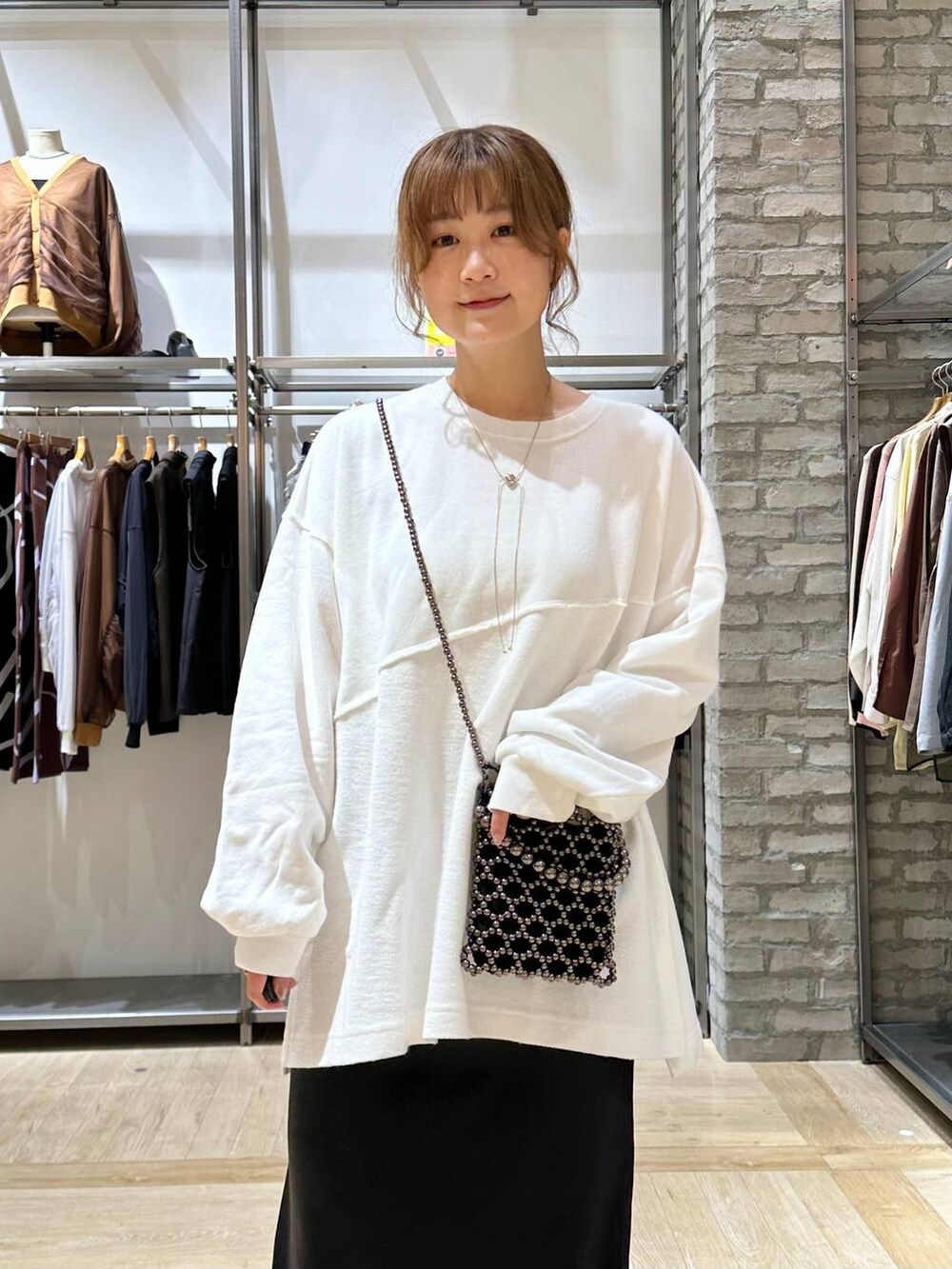 ブラック系のショルダーバッグ、ブラック系のスカート、ホワイト系のTシャツ/カットソーを着用したレディースの秋コーディネートの5枚目の写真