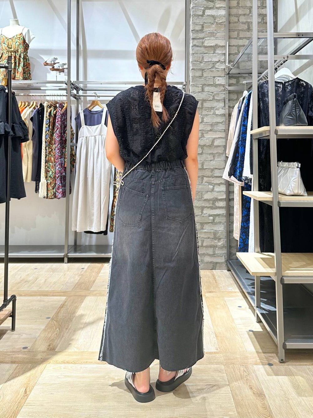 ホワイト系のTシャツ/カットソー、シルバー系のサンダル、ブラック系のデニムスカートを着用したレディースの夏コーディネートの3枚目の写真