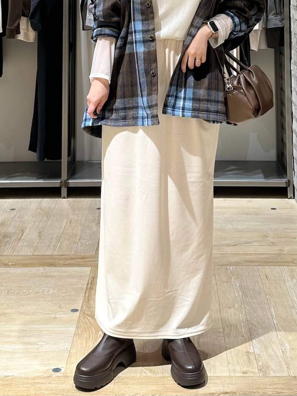 ブラウン系のショルダーバッグ、ブラウン系のブーツ、ホワイト系のTシャツ/カットソーを着用したレディースの秋コーディネートの5枚目の写真