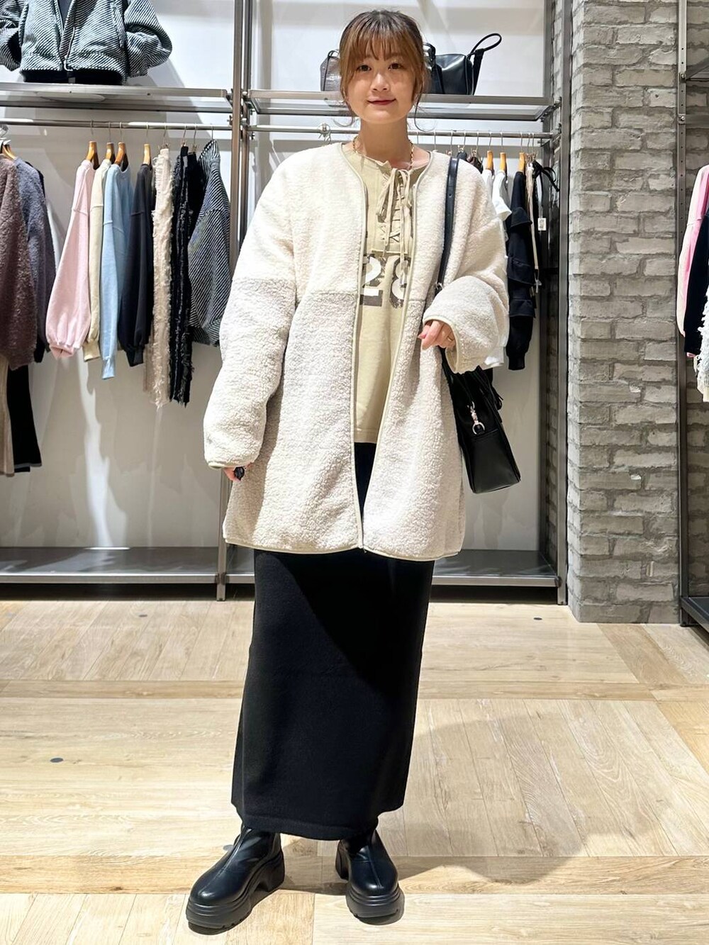 ブラック系のショルダーバッグ、ブラック系のスカート、ホワイト系のその他アウターを着用したレディースの秋コーディネートの8枚目の写真