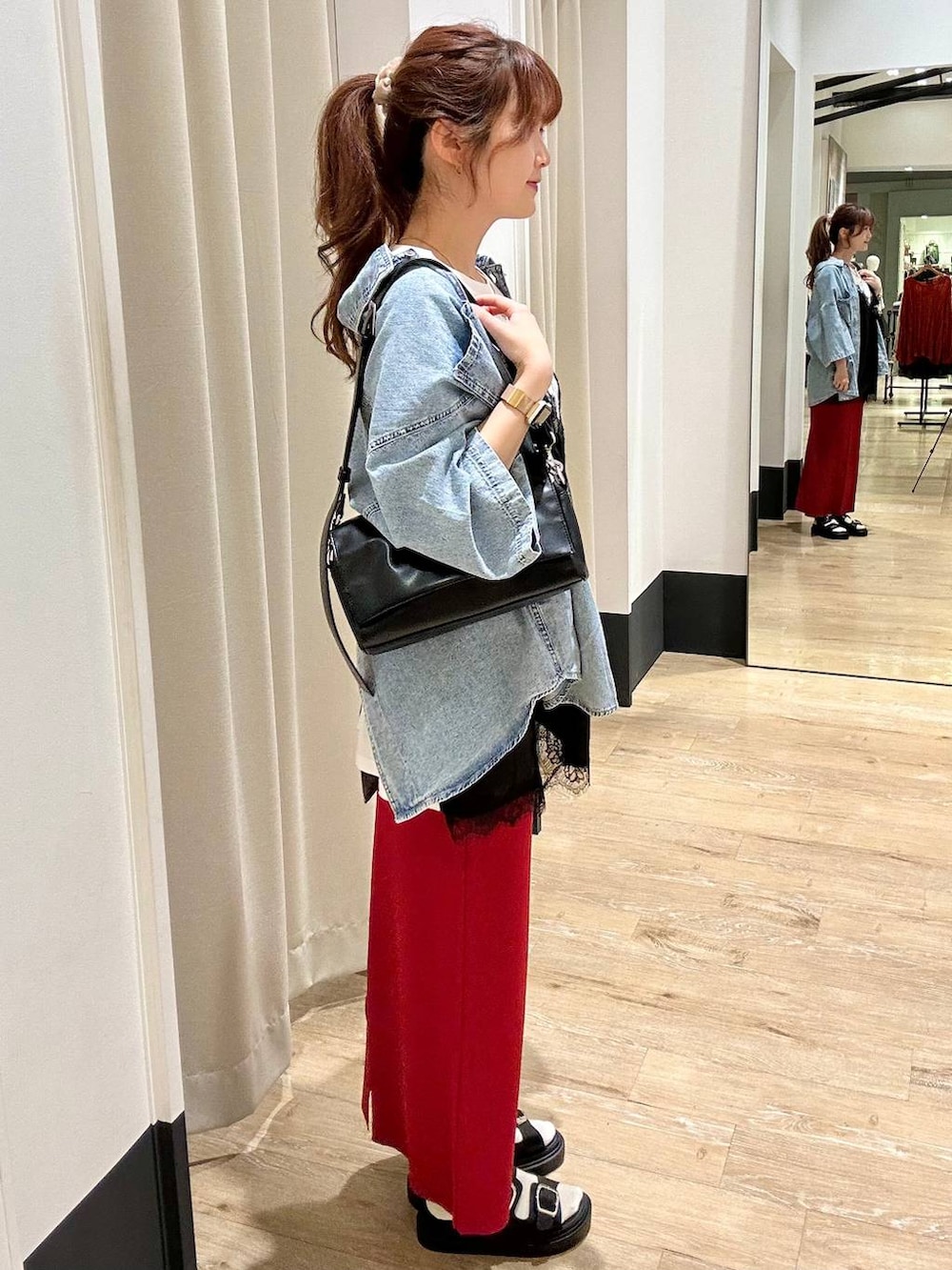 レッド系のスカート、ブラック系のショルダーバッグ、ブラック系のサンダルを着用したレディースの春コーディネートの2枚目の写真