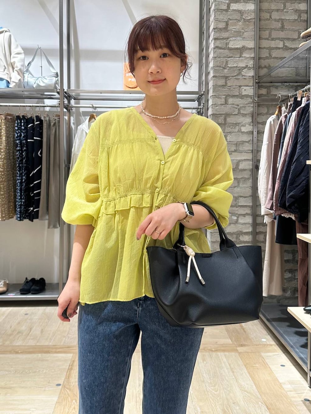 ブラック系のパンプス、ブラック系のトートバッグ、ブルー系のデニムパンツを着用したレディースの春コーディネートの4枚目の写真