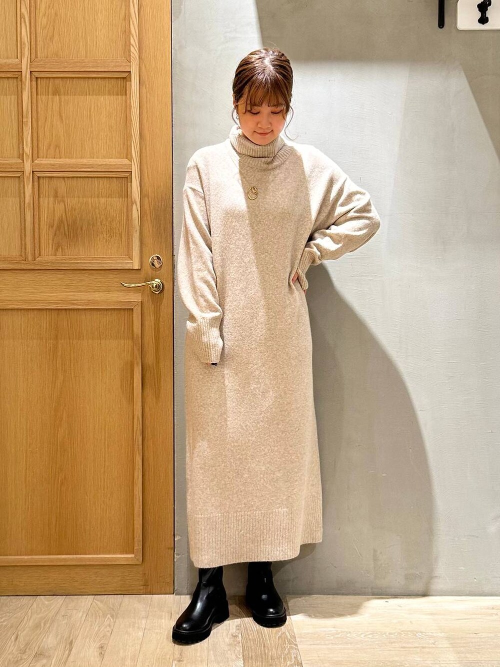 ブラック系のショルダーバッグ、ブラック系のブーツ、ベージュ系のワンピースを着用したレディースの冬コーディネートの3枚目の写真