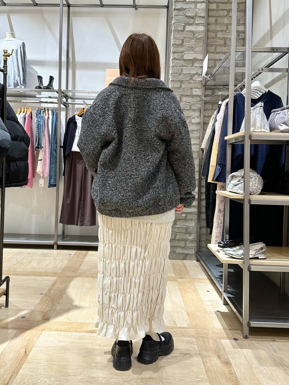 ブラック系のスニーカー、ホワイト系のスカート、グレー系のブルゾンを着用したレディースの秋コーディネートの3枚目の写真