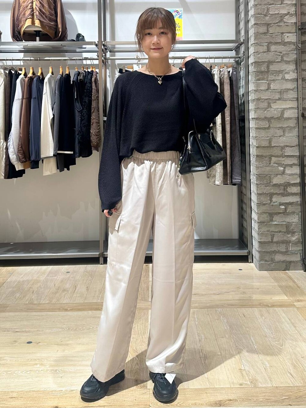 ブラック系のニット/セーター、ブラック系のスニーカー、ホワイト系のその他パンツを着用したレディースの秋コーディネートの2枚目の写真