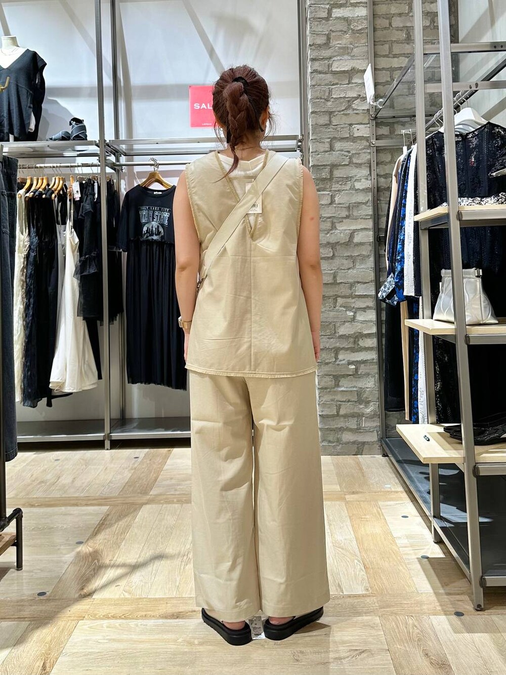 ホワイト系のショルダーバッグ、ホワイト系のベスト、ホワイト系のサンダルを着用したレディースの夏コーディネートの3枚目の写真