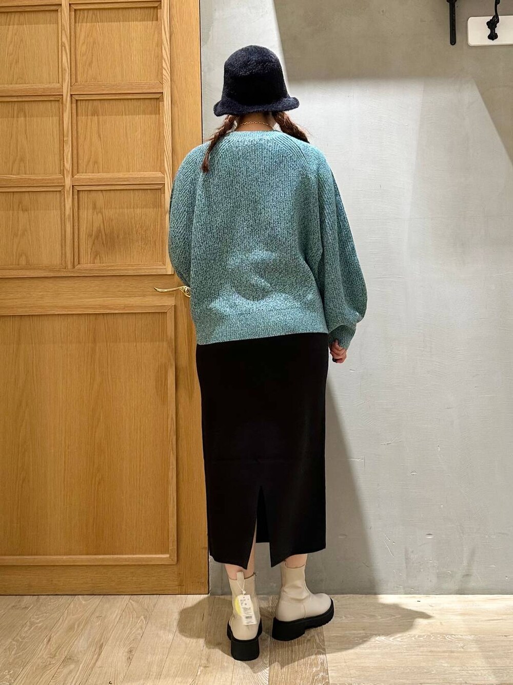 ブラック系のスカート、ホワイト系のブーツ、シルバー系のショルダーバッグを着用したレディースの秋コーディネートの4枚目の写真