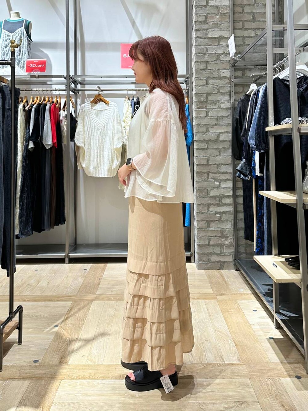 ベージュ系のスカート、ホワイト系のシャツ/ブラウス、ブラック系のサンダルを着用したレディースの夏コーディネートの3枚目の写真