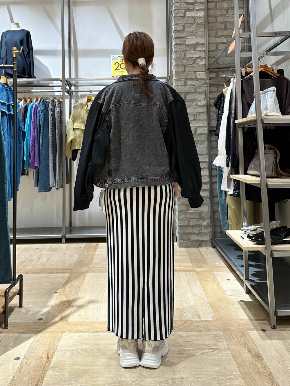 シルバー系のボストンバッグ、ホワイト系のスニーカー、ブラック系のスカートを着用したレディースの秋コーディネートの3枚目の写真