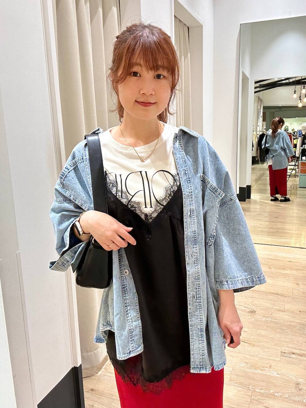 レッド系のスカート、ブラック系のショルダーバッグ、ブラック系のサンダルを着用したレディースの春コーディネートの4枚目の写真