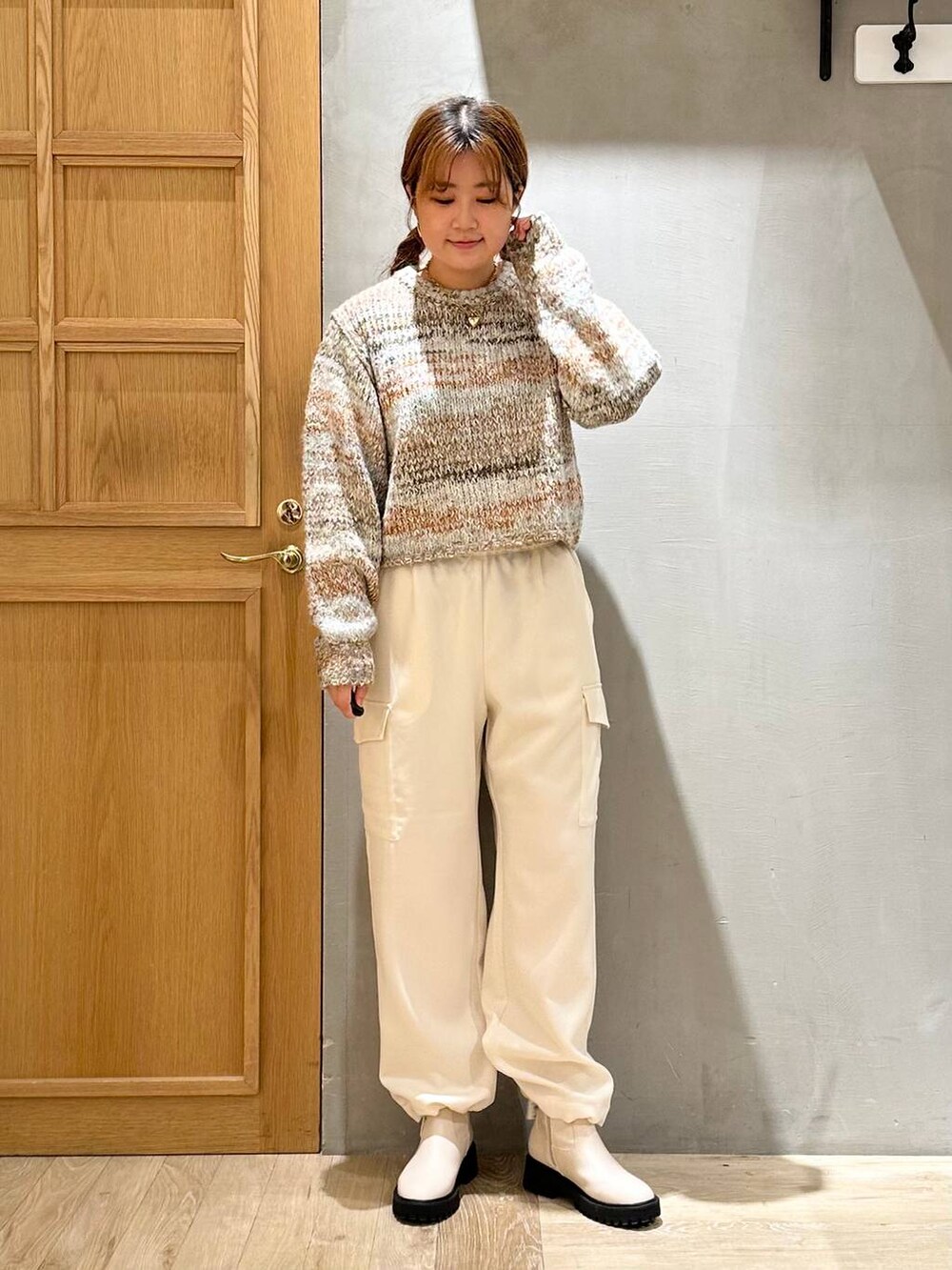 ブラウン系のノーカラーコート、ホワイト系のブーツ、ホワイト系のショルダーバッグを着用したレディースの秋コーディネートの5枚目の写真