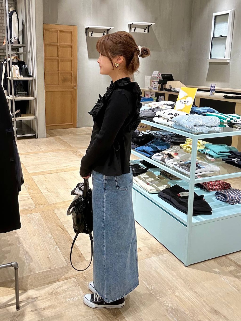 ブラック系のTシャツ/カットソー、ブルー系のデニムスカート、ブラック系のショルダーバッグを着用したレディースの春コーディネートの2枚目の写真