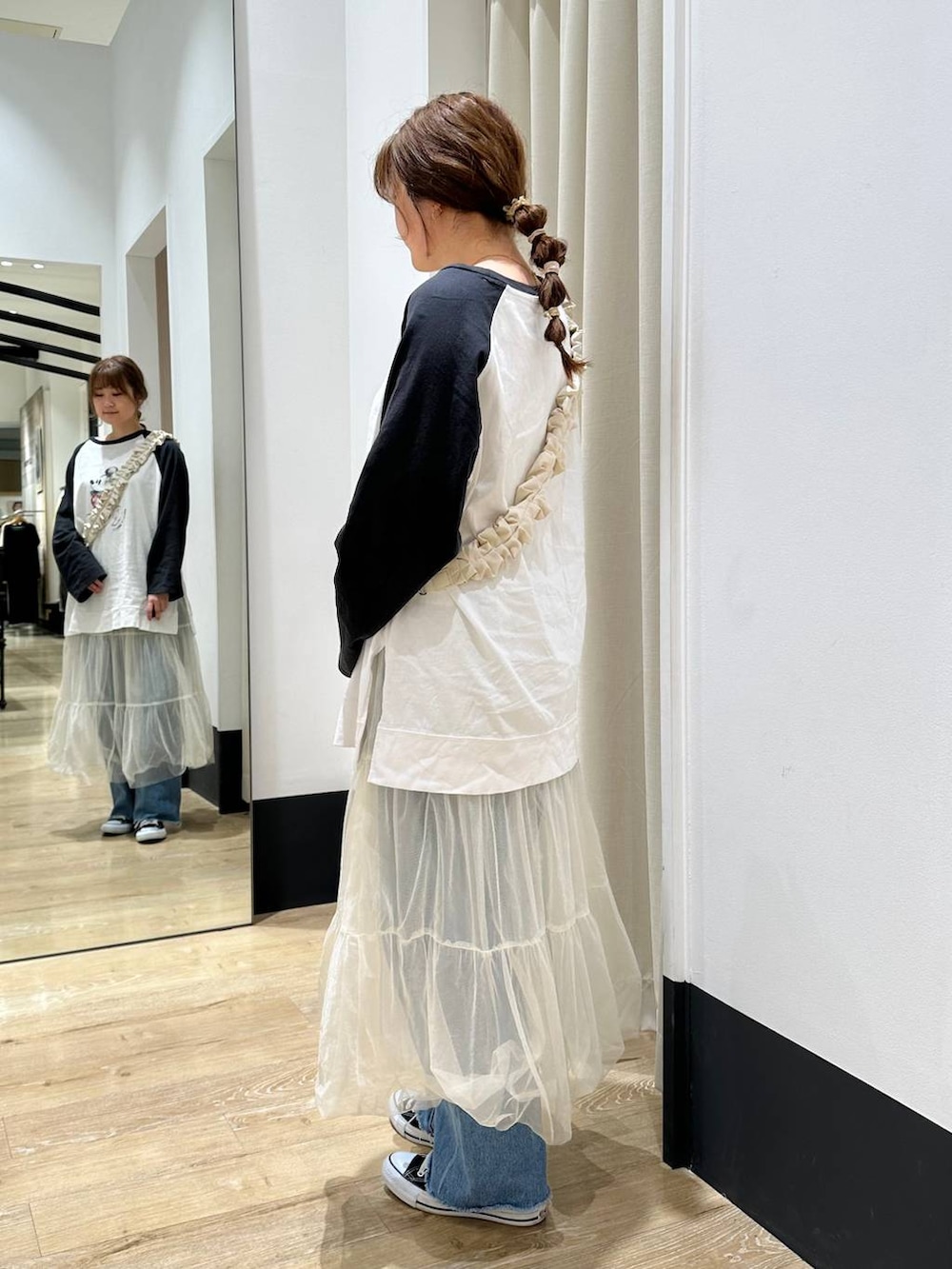 ホワイト系のスカート、ブラック系のTシャツ/カットソー、ブルー系のデニムパンツを着用したレディースの春コーディネートの4枚目の写真