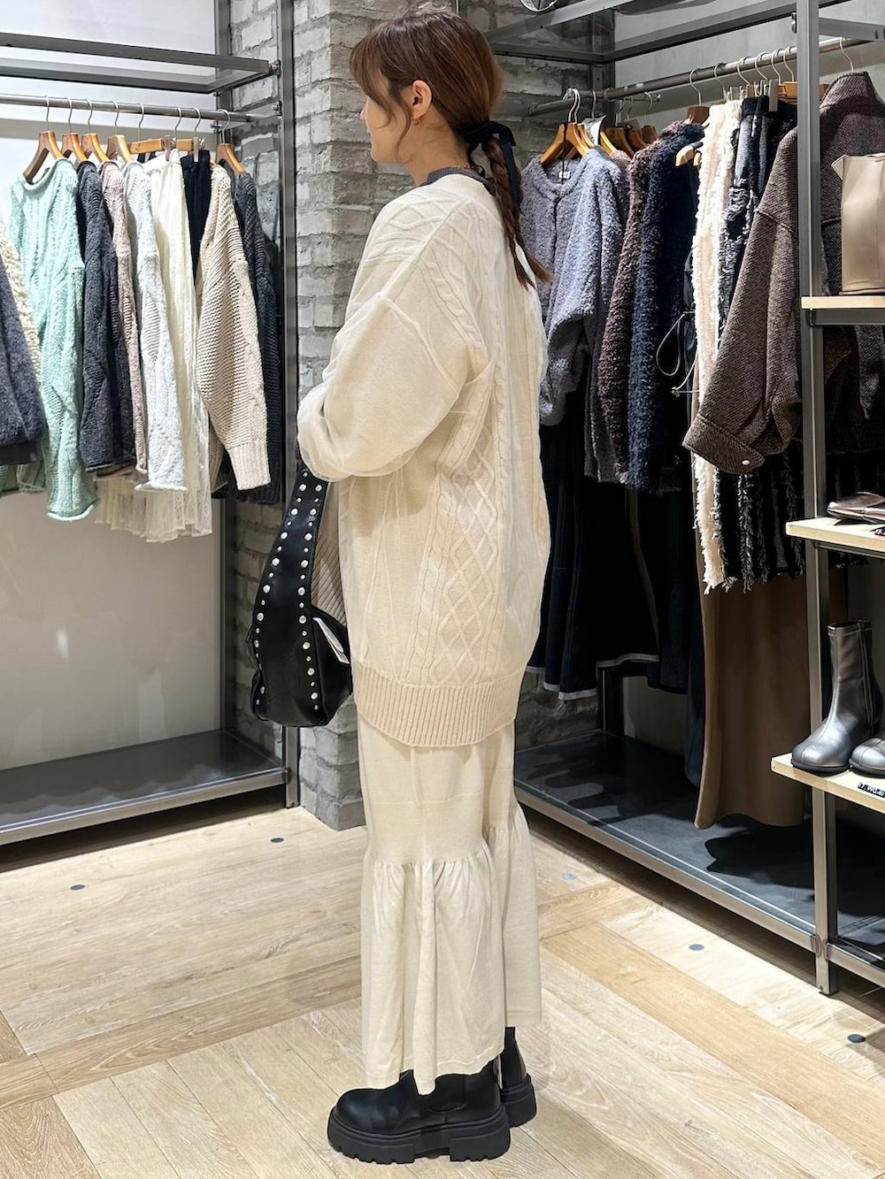 ホワイト系のスカート、グレー系のニット/セーター、ブラック系のブーツを着用したレディースの秋コーディネートの2枚目の写真