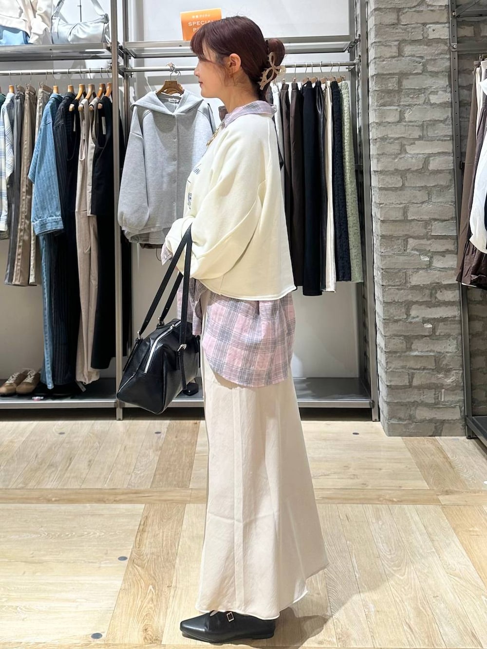 ブラック系のボストンバッグ、ベージュ系のスカート、ホワイト系のスウェットを着用したレディースの春コーディネートの2枚目の写真