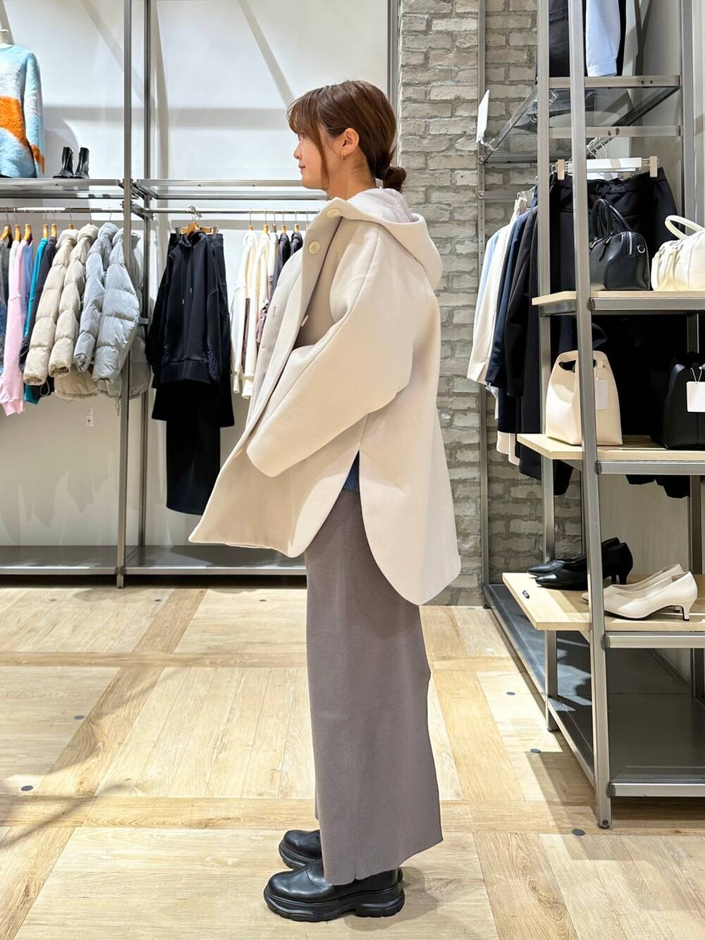 ホワイト系のポンチョ、グレー系のスカート、ブラック系のブーツを着用したレディースの冬コーディネートの2枚目の写真