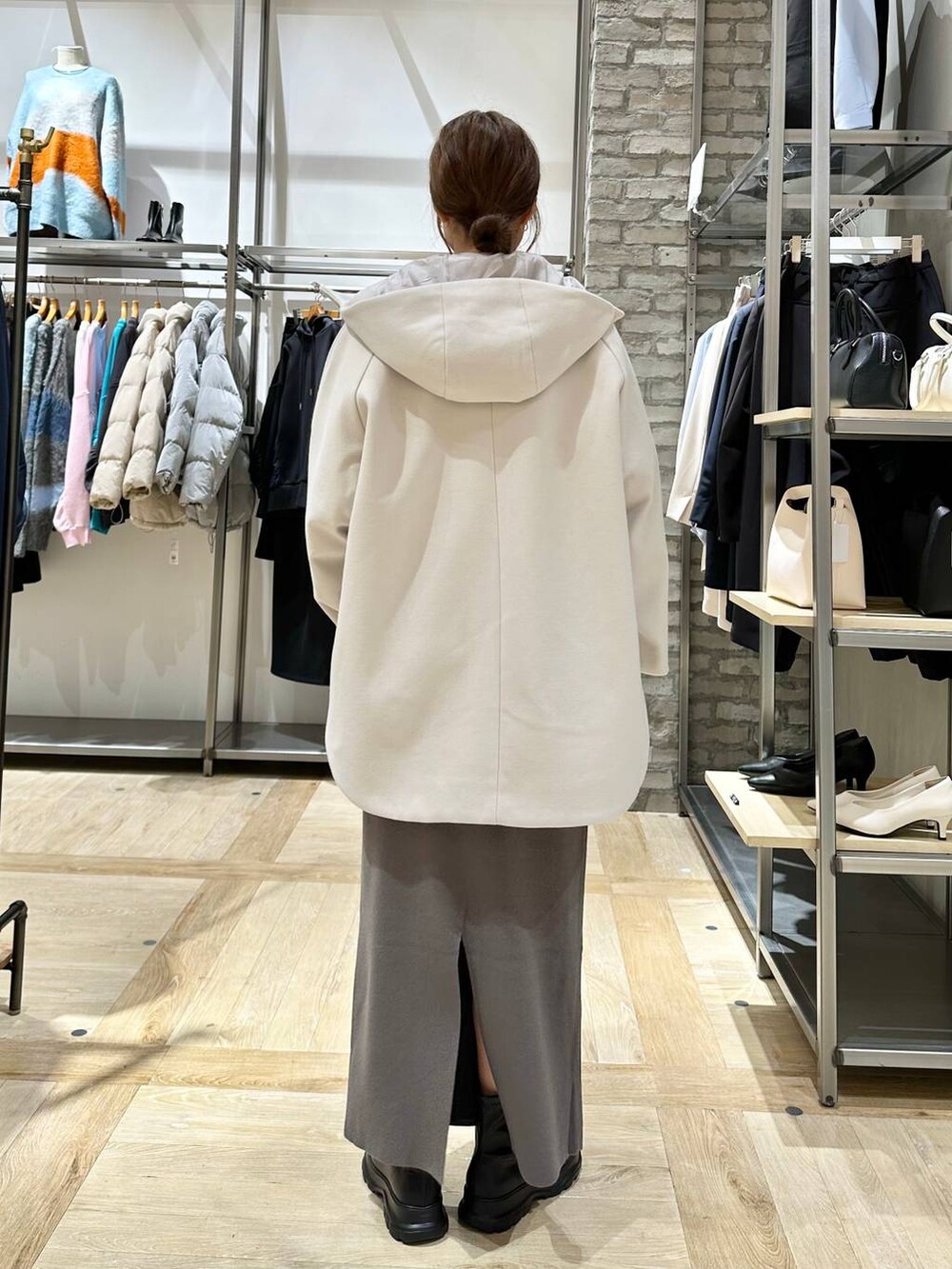 ホワイト系のポンチョ、グレー系のスカート、ブラック系のブーツを着用したレディースの冬コーディネートの3枚目の写真