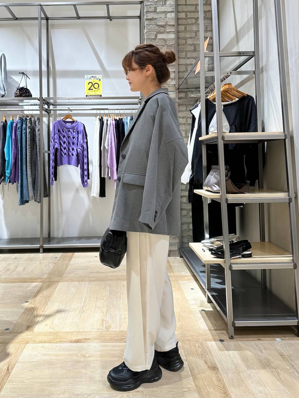 グレー系のテーラードジャケット、ブラック系のスニーカー、ブラック系のボストンバッグを着用したレディースの秋コーディネートの2枚目の写真