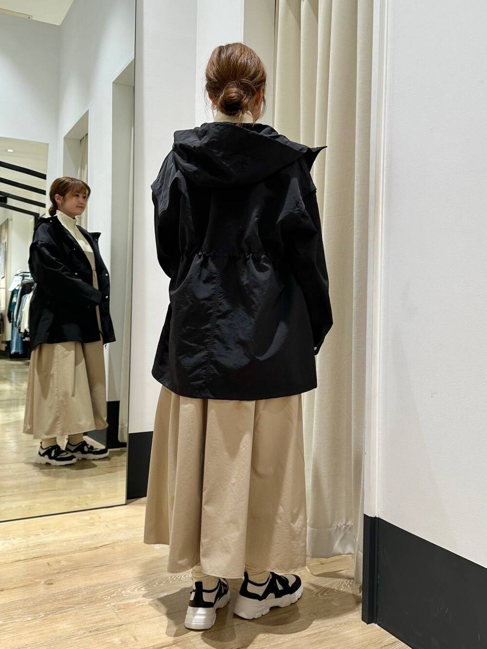 ベージュ系のワンピース、ブラック系のその他アウター、ホワイト系のスニーカーを着用したレディースの冬コーディネートの4枚目の写真