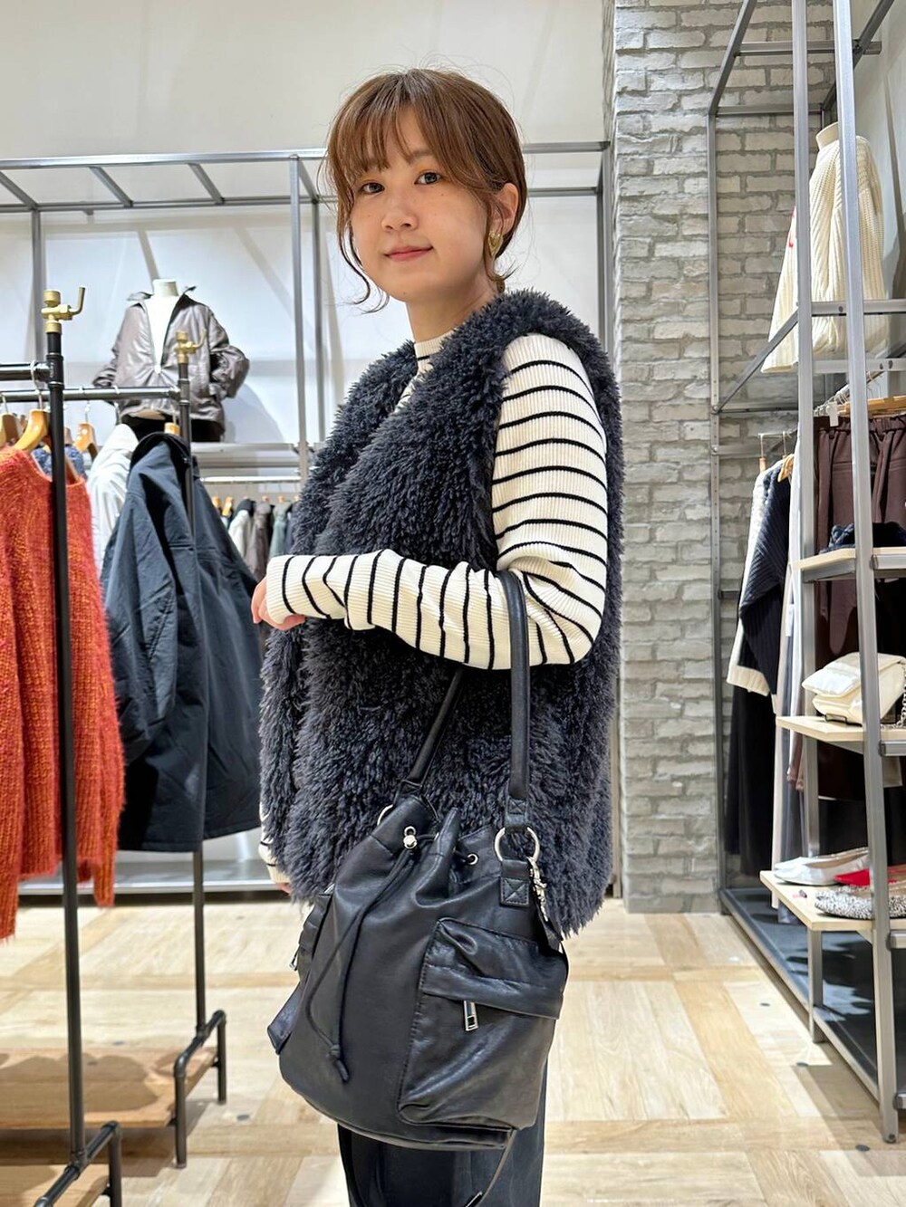 ブラック系のブーツ、ホワイト系のニット/セーター、ブラック系のショルダーバッグを着用したレディースの秋コーディネートの5枚目の写真