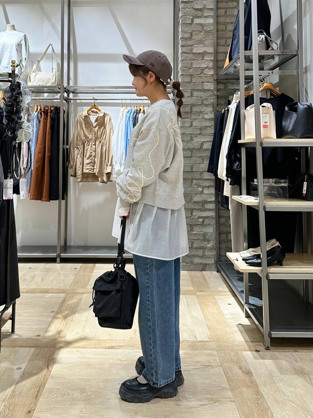 ブラック系のショルダーバッグ、ブラック系のスニーカー、ホワイト系のTシャツ/カットソーを着用したレディースの春コーディネートの2枚目の写真