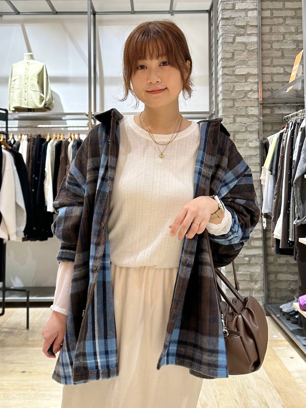 ブラウン系のショルダーバッグ、ブラウン系のブーツ、ホワイト系のTシャツ/カットソーを着用したレディースの秋コーディネートの4枚目の写真