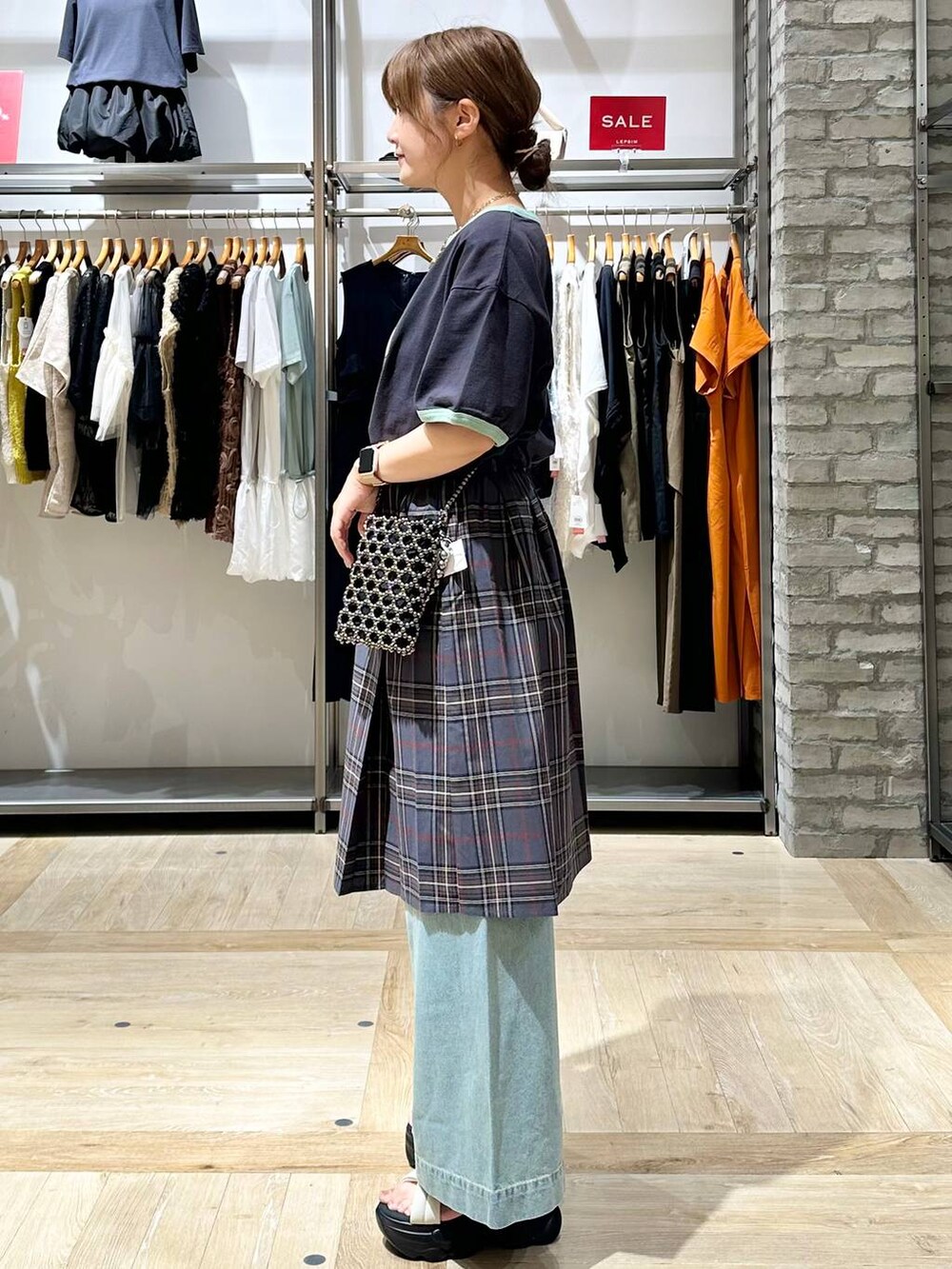 ブルー系のデニムパンツ、シルバー系のショルダーバッグ、ホワイト系のサンダルを着用したレディースの夏コーディネートの3枚目の写真