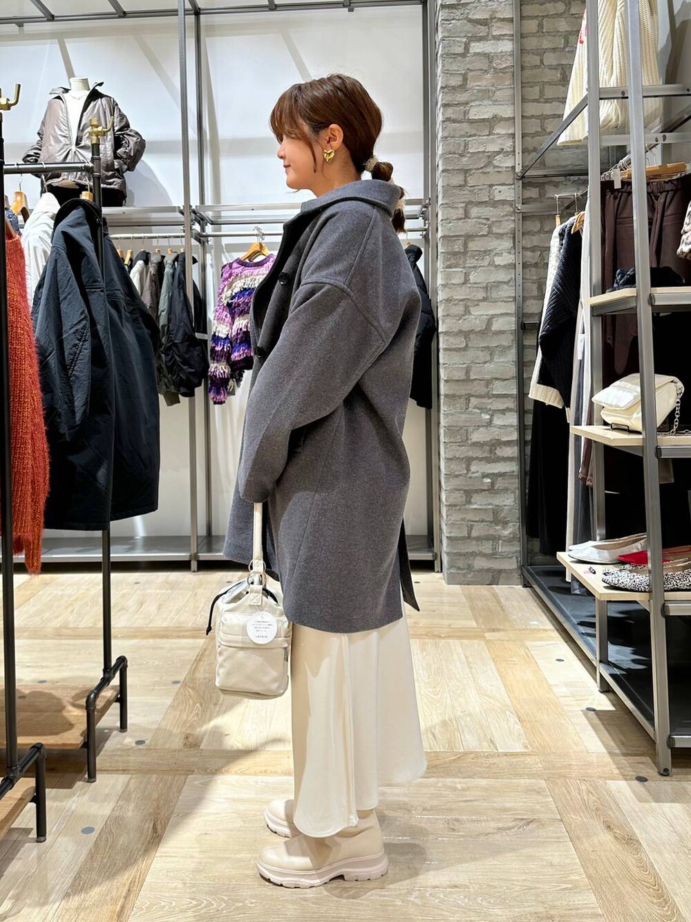 グレー系のその他アウター、ホワイト系のスカート、ホワイト系のブーツを着用したレディースの冬コーディネートの2枚目の写真