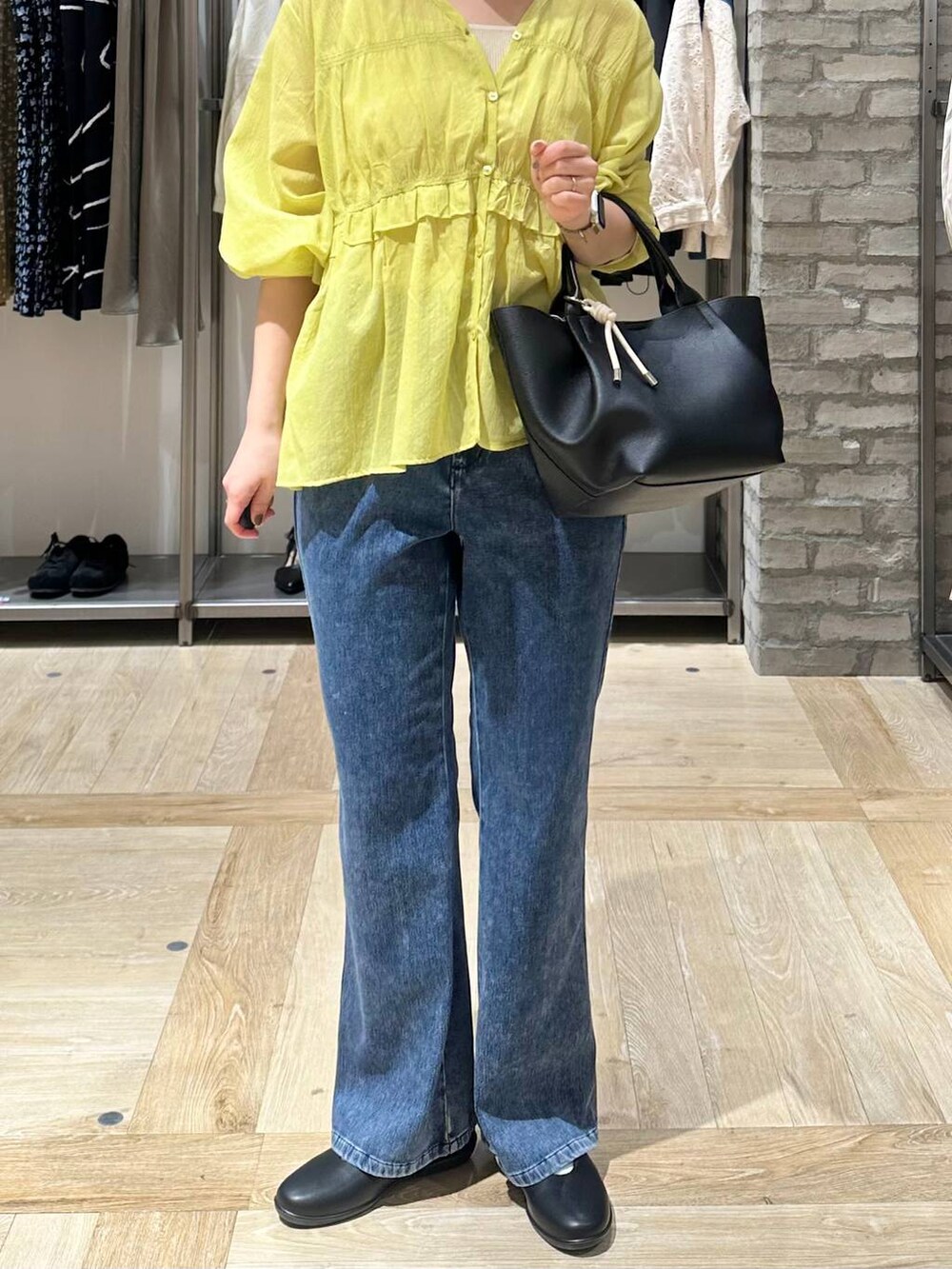 ブラック系のパンプス、ブラック系のトートバッグ、ブルー系のデニムパンツを着用したレディースの春コーディネートの5枚目の写真