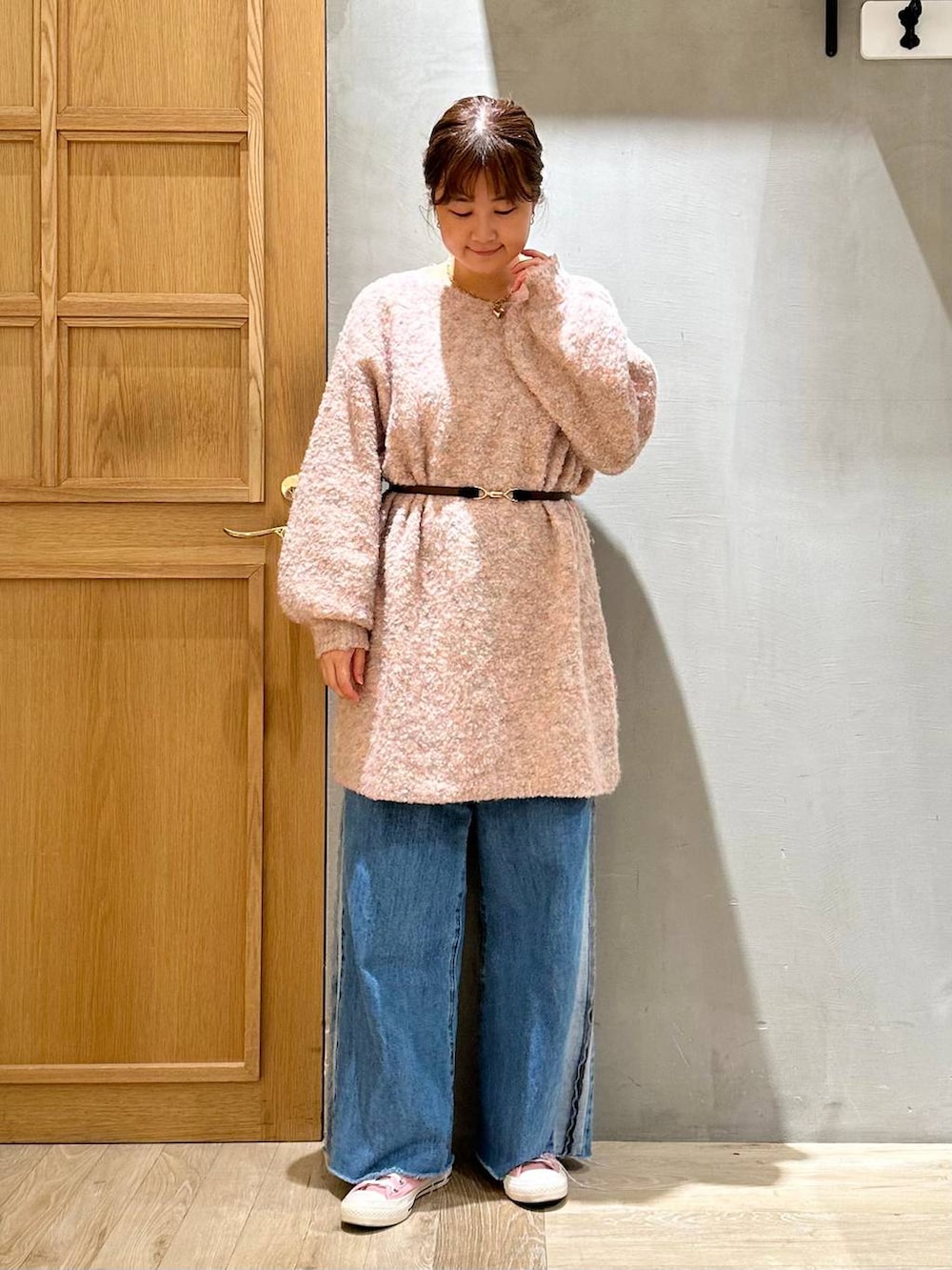 ピンク系のワンピース、ブルー系のデニムパンツ、ブラウン系のネックレスを着用したレディースの冬コーディネートの2枚目の写真