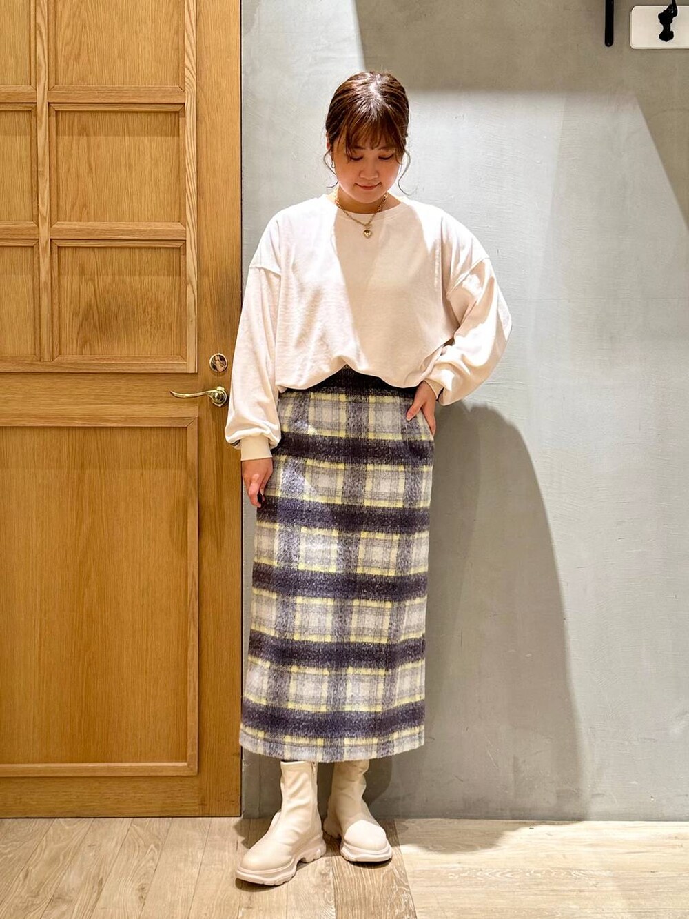 グレー系のスカート、ブラック系のショルダーバッグ、ホワイト系のブーツを着用したレディースの冬コーディネートの2枚目の写真