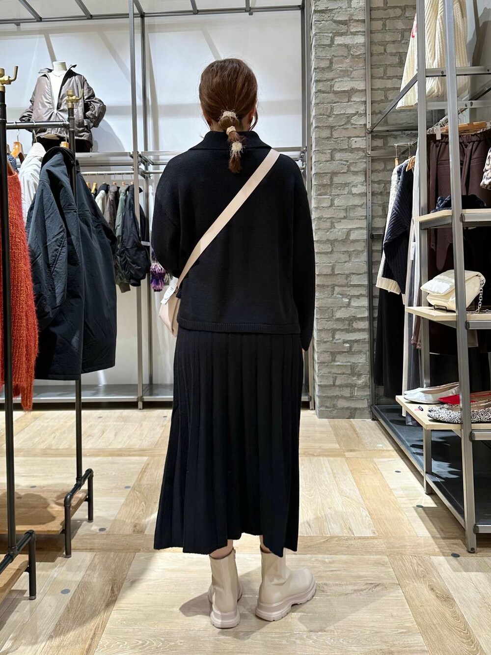 ホワイト系のブーツ、ホワイト系のショルダーバッグ、ブラック系のワンピースを着用したレディースの秋コーディネートの4枚目の写真