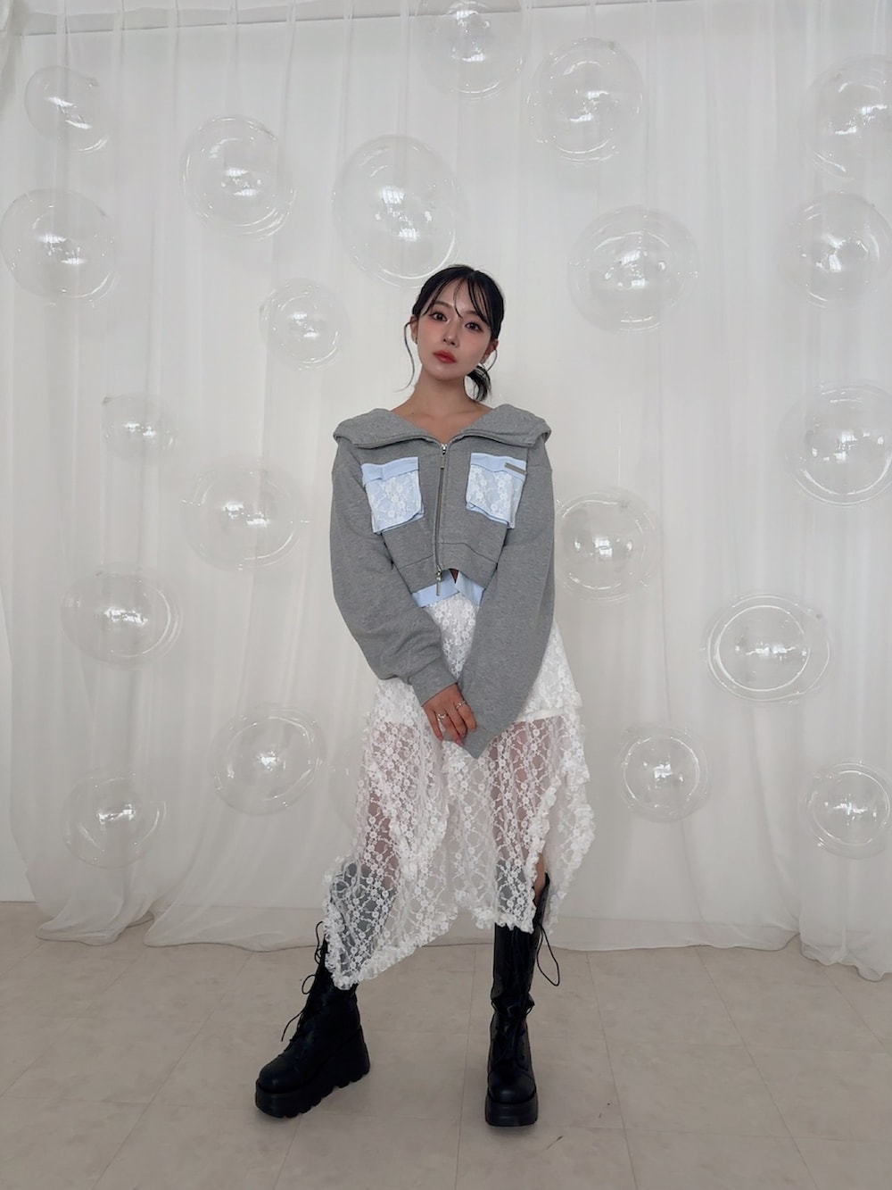 グレー系のパーカー、ホワイト系のスカートを着用したレディースの夏コーディネートの3枚目の写真