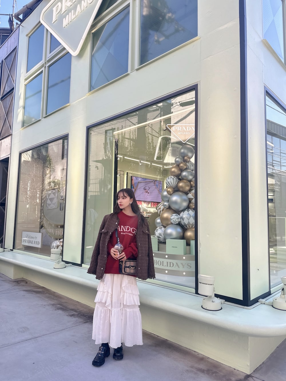 レッド系のニット/セーター、ブラウン系のその他アウター、ホワイト系のスカートを着用したレディースの冬コーディネートの4枚目の写真