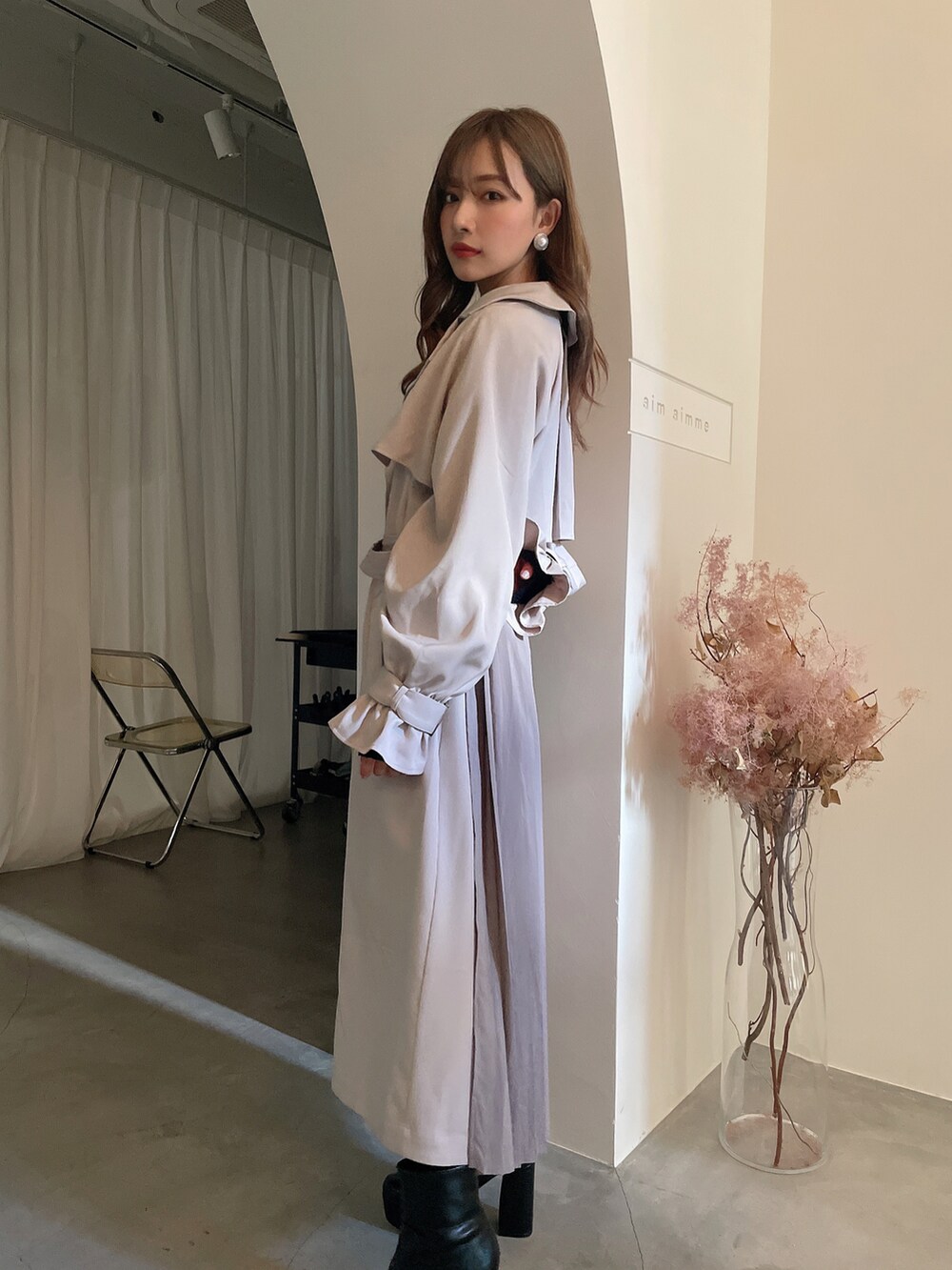 ブラック系のブーツ、グレー系のトレンチコートを着用したレディースの秋コーディネートの2枚目の写真