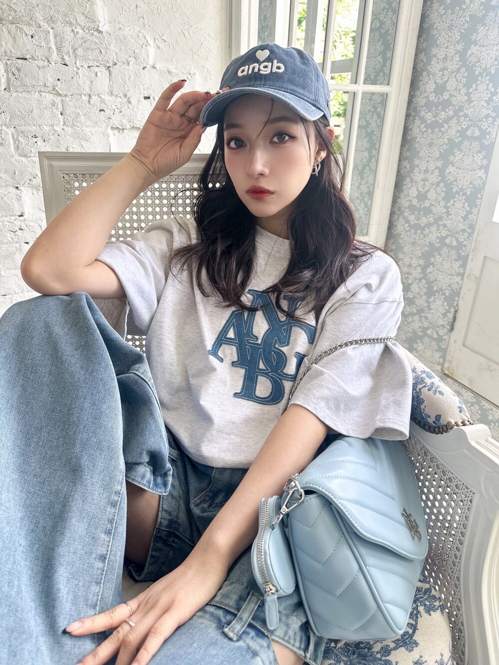 ブルー系のショルダーバッグ、グレー系のTシャツ/カットソー、ブルー系のキャップを着用したレディースの夏コーディネートの2枚目の写真