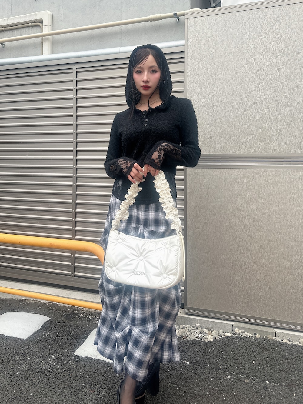 ブラック系のニット/セーター、ブルー系のスカート、ホワイト系のショルダーバッグを着用したレディースの秋コーディネートの2枚目の写真