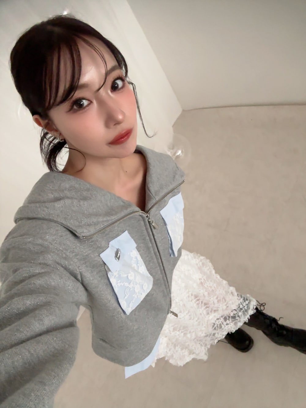 グレー系のパーカー、ホワイト系のスカートを着用したレディースの夏コーディネートの4枚目の写真