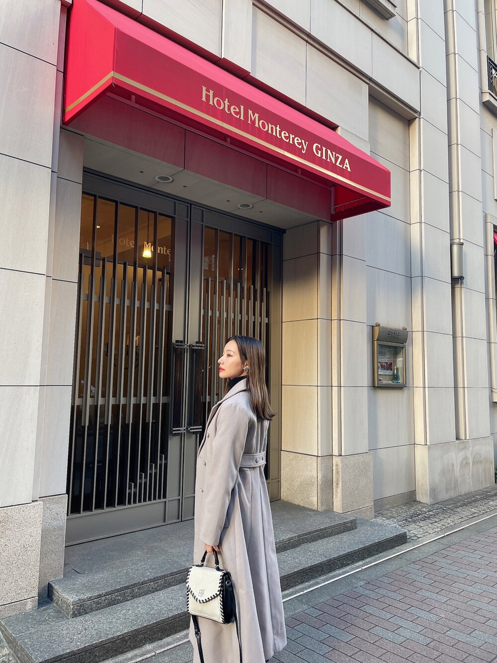 グレー系のチェスターコート、ブラック系のその他シューズ、ベージュ系のショルダーバッグを着用したレディースの春コーディネートの4枚目の写真