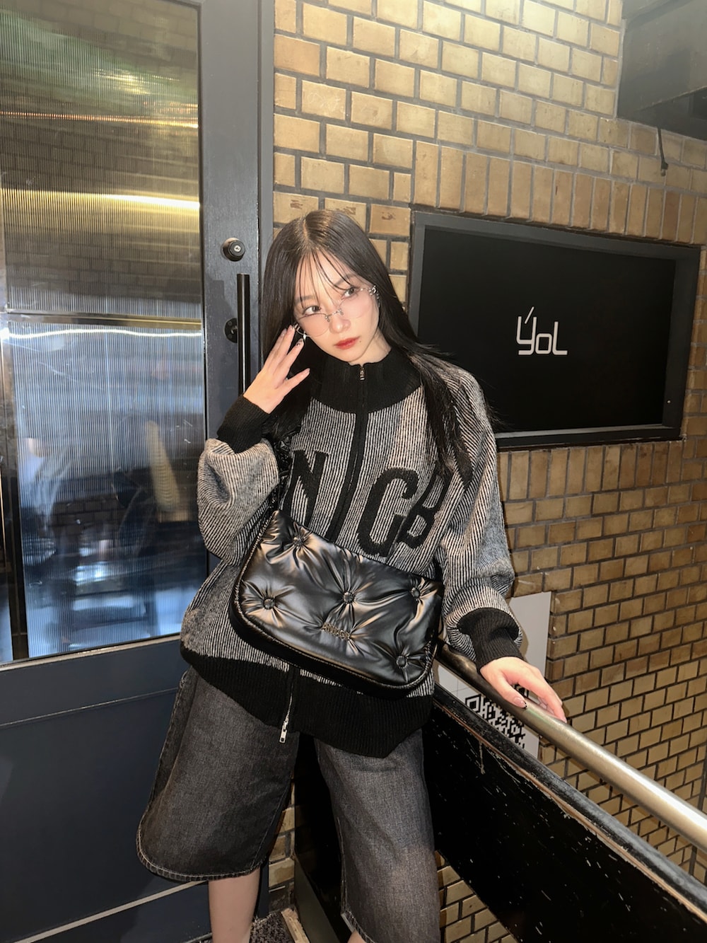 ブラック系のニット/セーター、ホワイト系のショルダーバッグ、ブラック系のデニムパンツを着用したレディースの冬コーディネートの3枚目の写真