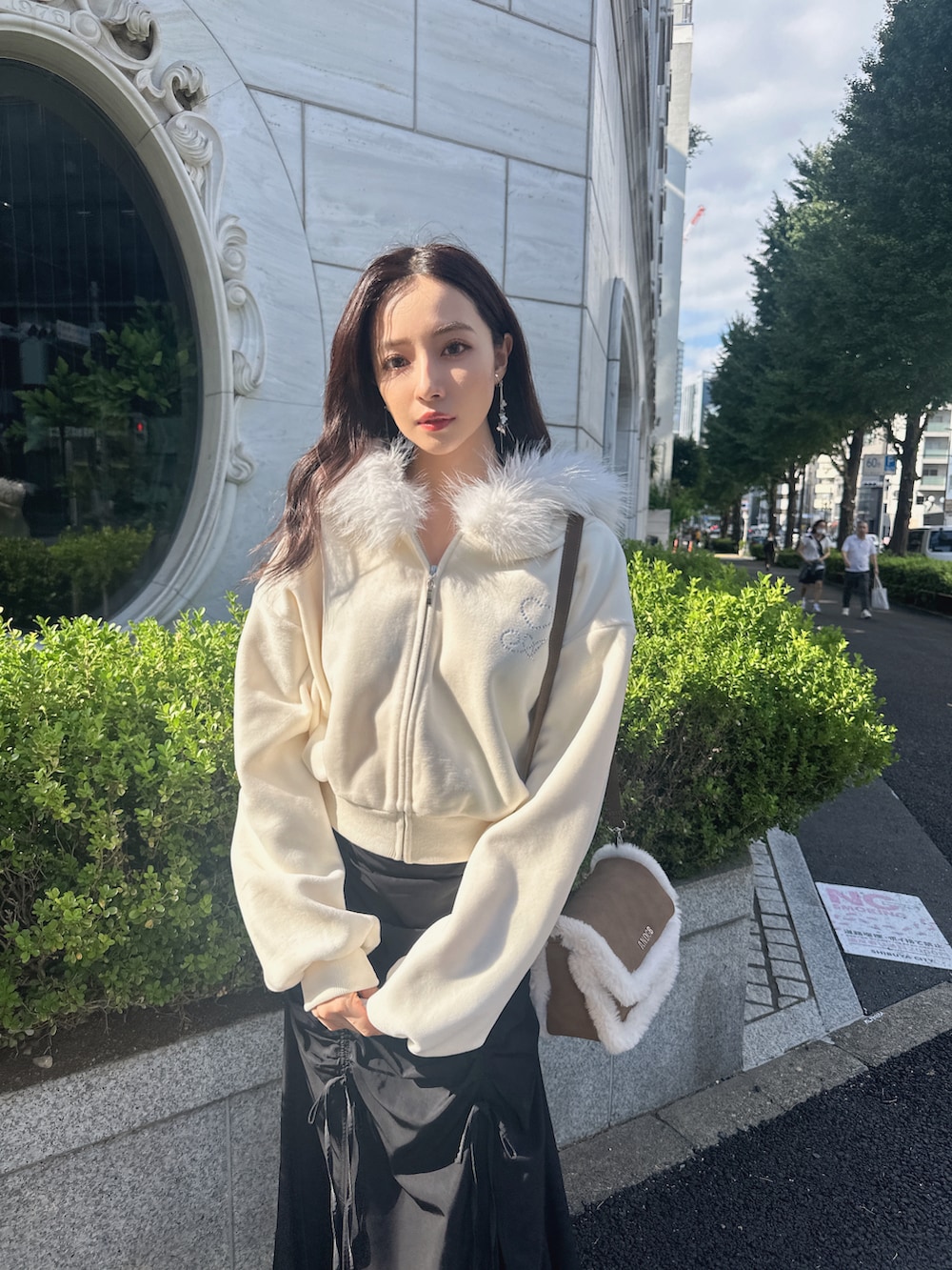 ブラウン系のショルダーバッグ、ホワイト系のパーカー、ブラック系のスカートを着用したレディースの冬コーディネートの3枚目の写真