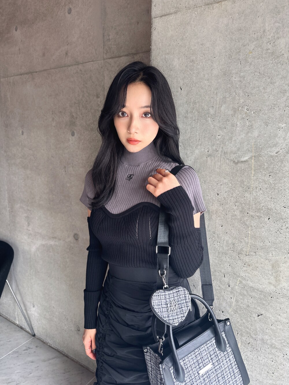 グレー系のニット/セーター、ブラック系のスカート、グレー系のショルダーバッグを着用したレディースの秋コーディネートの3枚目の写真