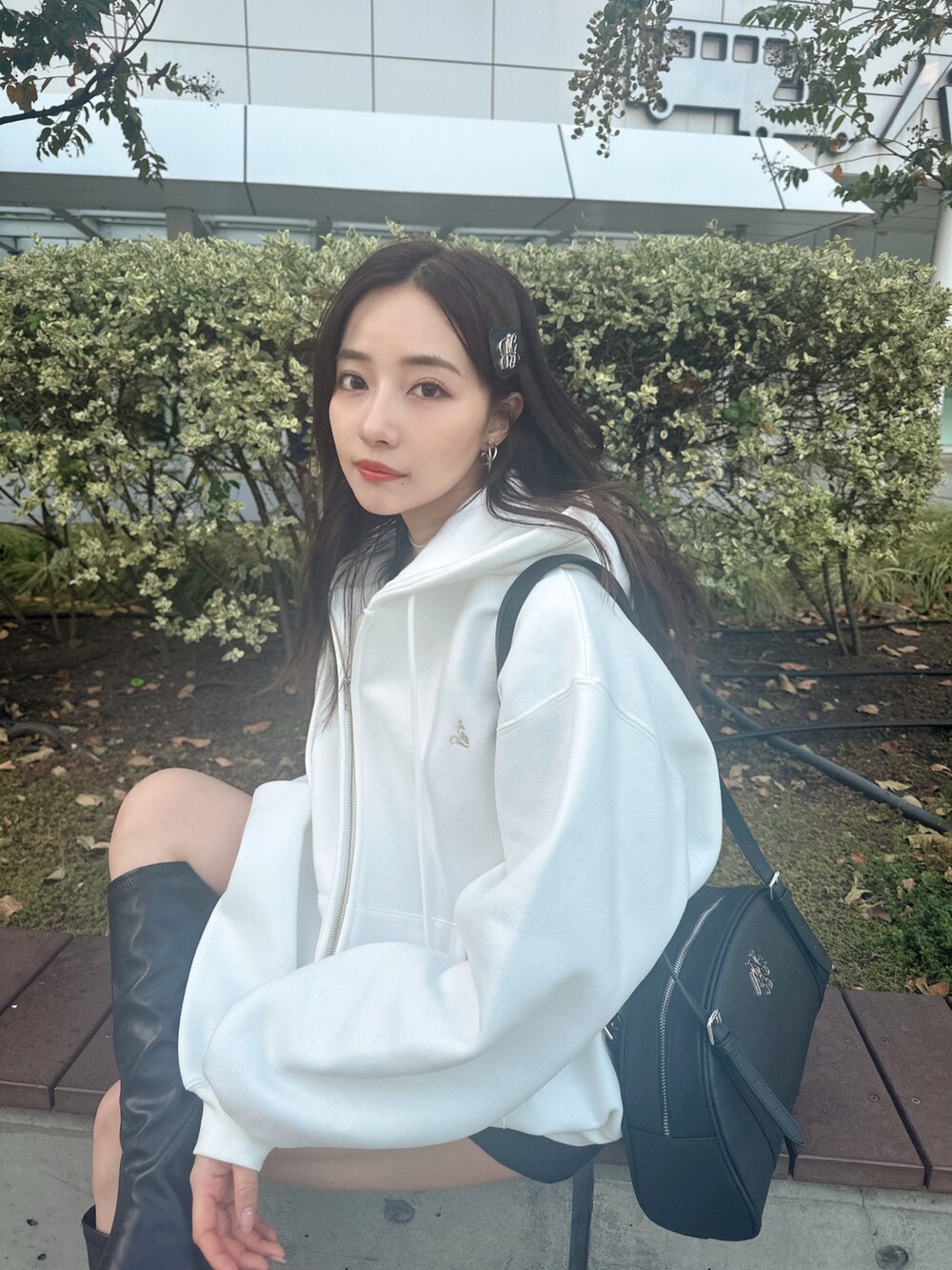 ブラック系のショルダーバッグ、ホワイト系のパーカーを着用したレディースの冬コーディネートの4枚目の写真