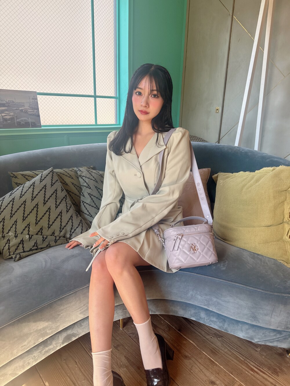 グリーン系のワンピース、パープル系のショルダーバッグを着用したレディースの春コーディネートの2枚目の写真