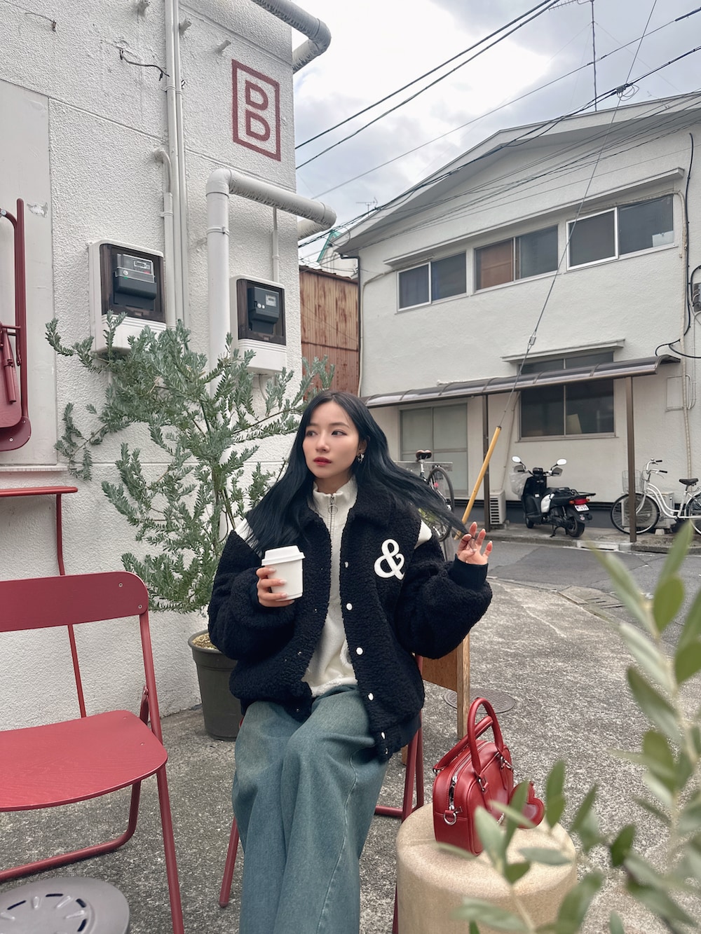 ブラック系のスタジャン、レッド系のショルダーバッグを着用したレディースの春コーディネートの2枚目の写真