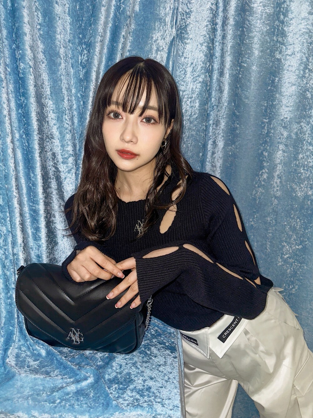 ブラック系のニット/セーター、グレー系のカーゴパンツ、ブラック系のショルダーバッグを着用したレディースの春コーディネートの4枚目の写真