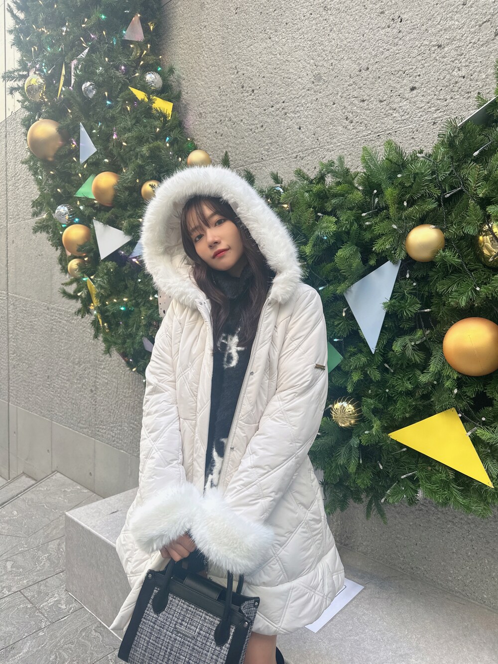 ホワイト系のダウンジャケット/コート、ブラック系のワンピース、グレー系のショルダーバッグを着用したレディースの春コーディネートの2枚目の写真