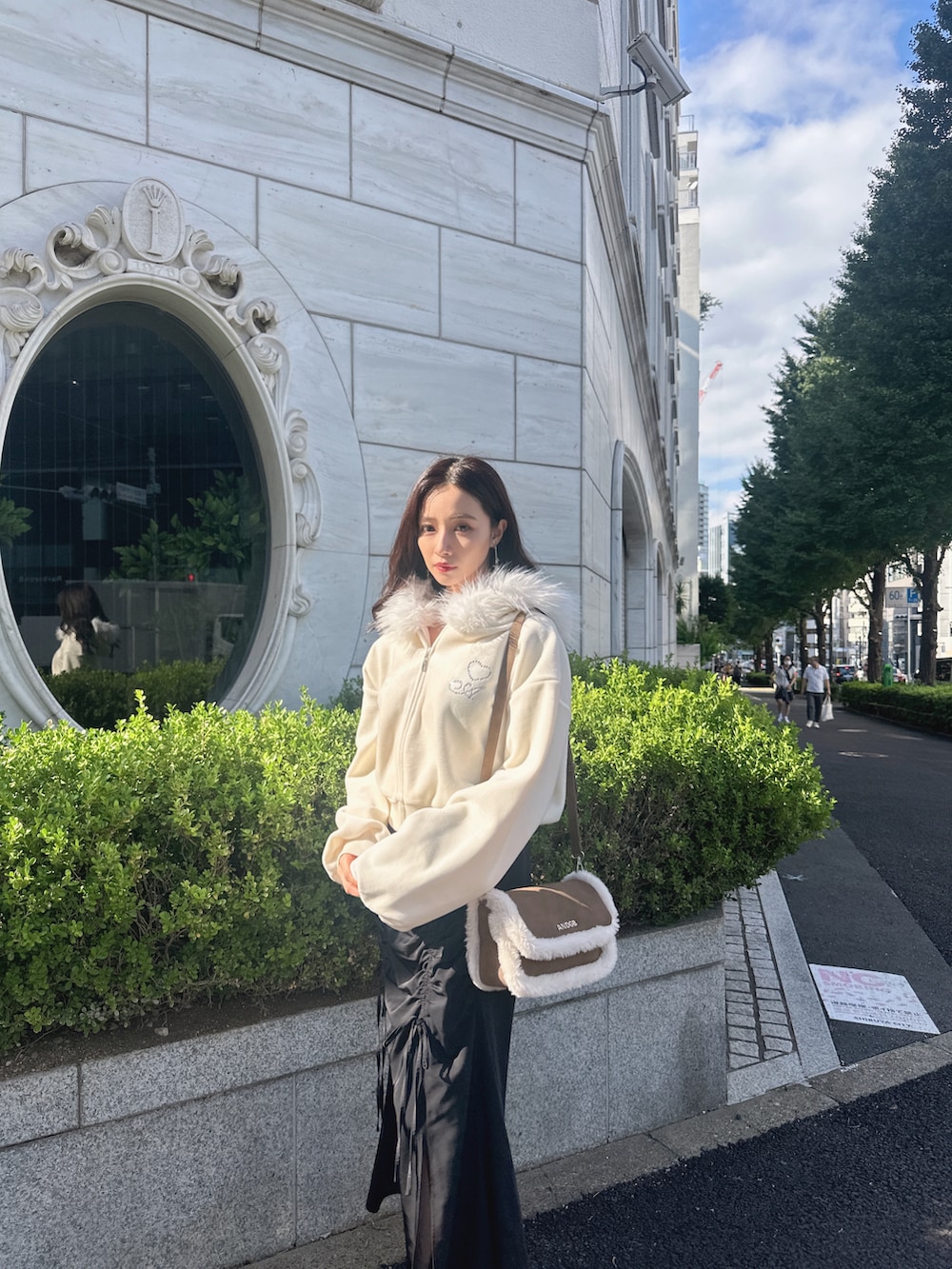 ブラウン系のショルダーバッグ、ホワイト系のパーカー、ブラック系のスカートを着用したレディースの冬コーディネートの2枚目の写真