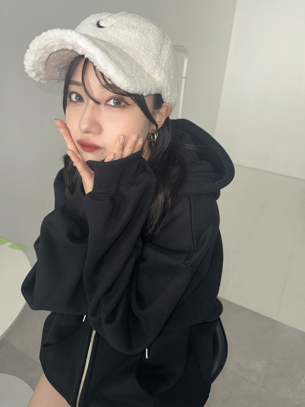 ブラック系のパーカー、ホワイト系のキャップを着用したレディースの秋コーディネートの2枚目の写真